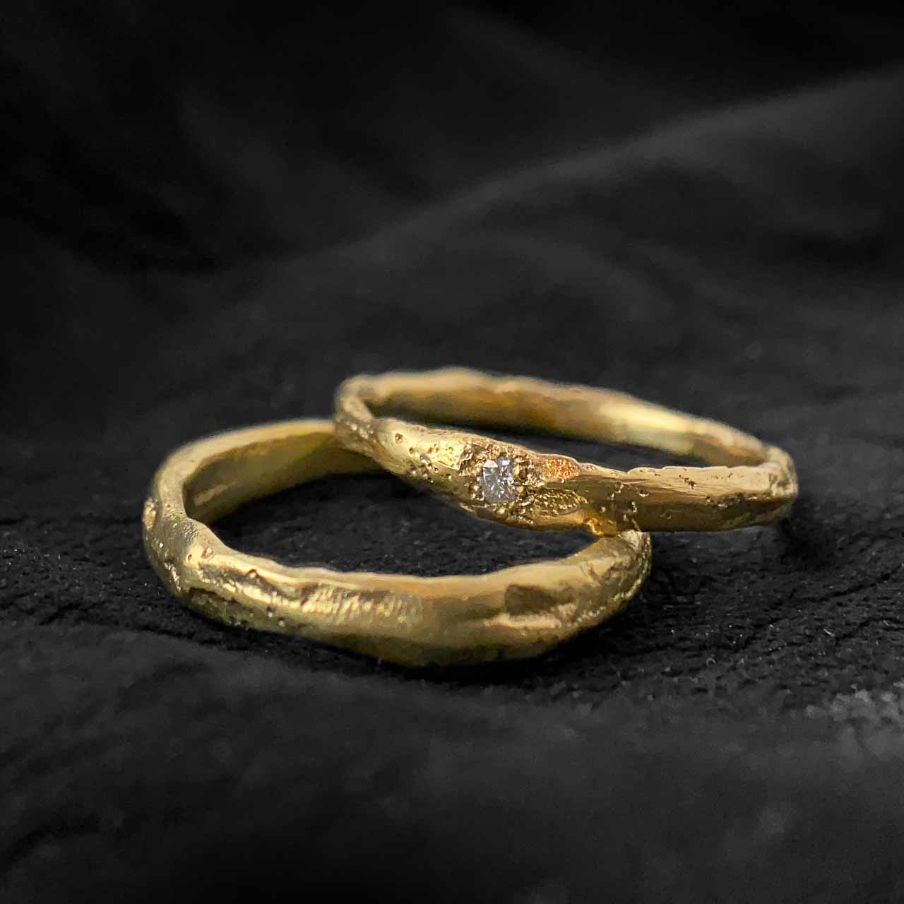 two wedding bands in yellow gold on a dark background.