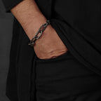Man wearing an oxidised sterling silver chain link bracelet with big links and a raw texture, handcrafted in Berlin.