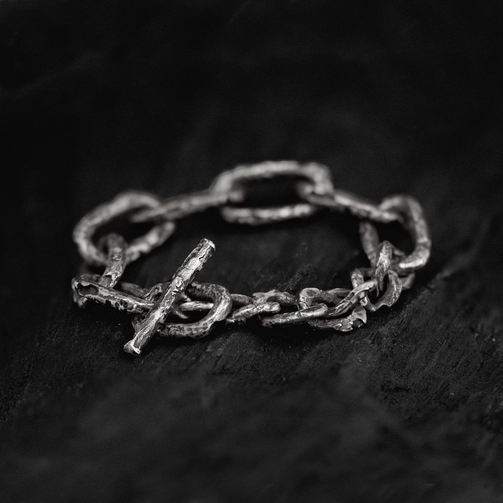 Oxidised sterling silver link chain bracelet with a big toggle clasp and lots of texture, handcrafted in Berlin on a dark background.