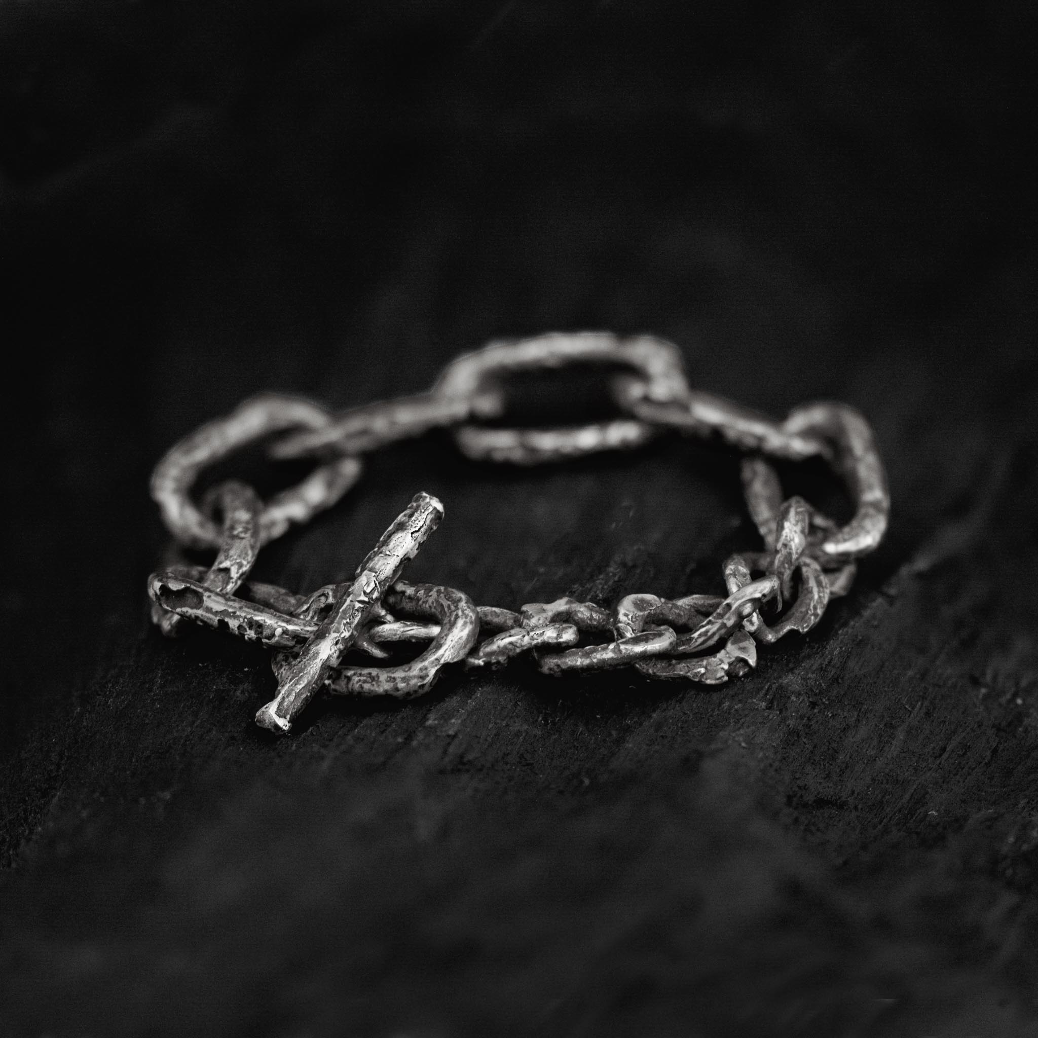 Oxidised sterling silver link chain bracelet with a big toggle clasp and lots of texture, handcrafted in Berlin on a dark background.