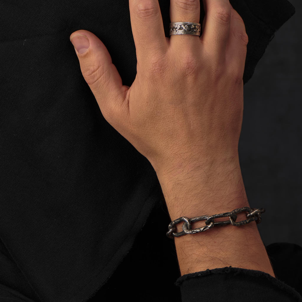 A wrist with a big handcrafted chain link bracelet in oxidised silver showing its rock and roll character.