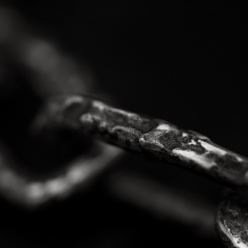 Close up of one of the textured links of this handcrafted, oxidised sterling silver chain link bracelet.