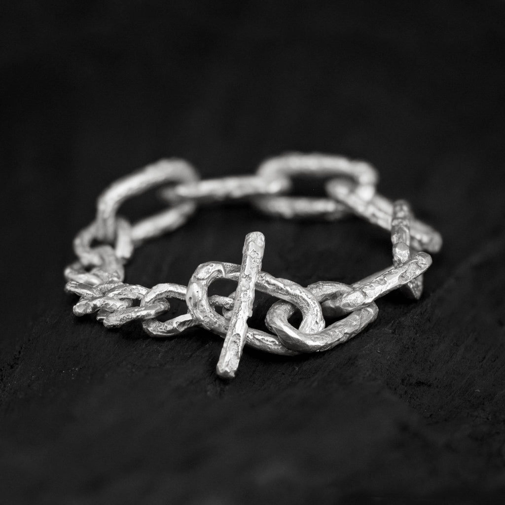 Sterling silver link chain bracelet with a big toggle clasp and lots of texture, handcrafted in Berlin on a dark background.