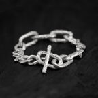 Sterling silver link chain bracelet with a big toggle clasp and lots of texture, handcrafted in Berlin on a dark background.