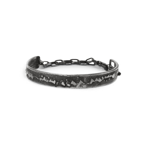 Silver cuff bracelet with texture and chain on a white background