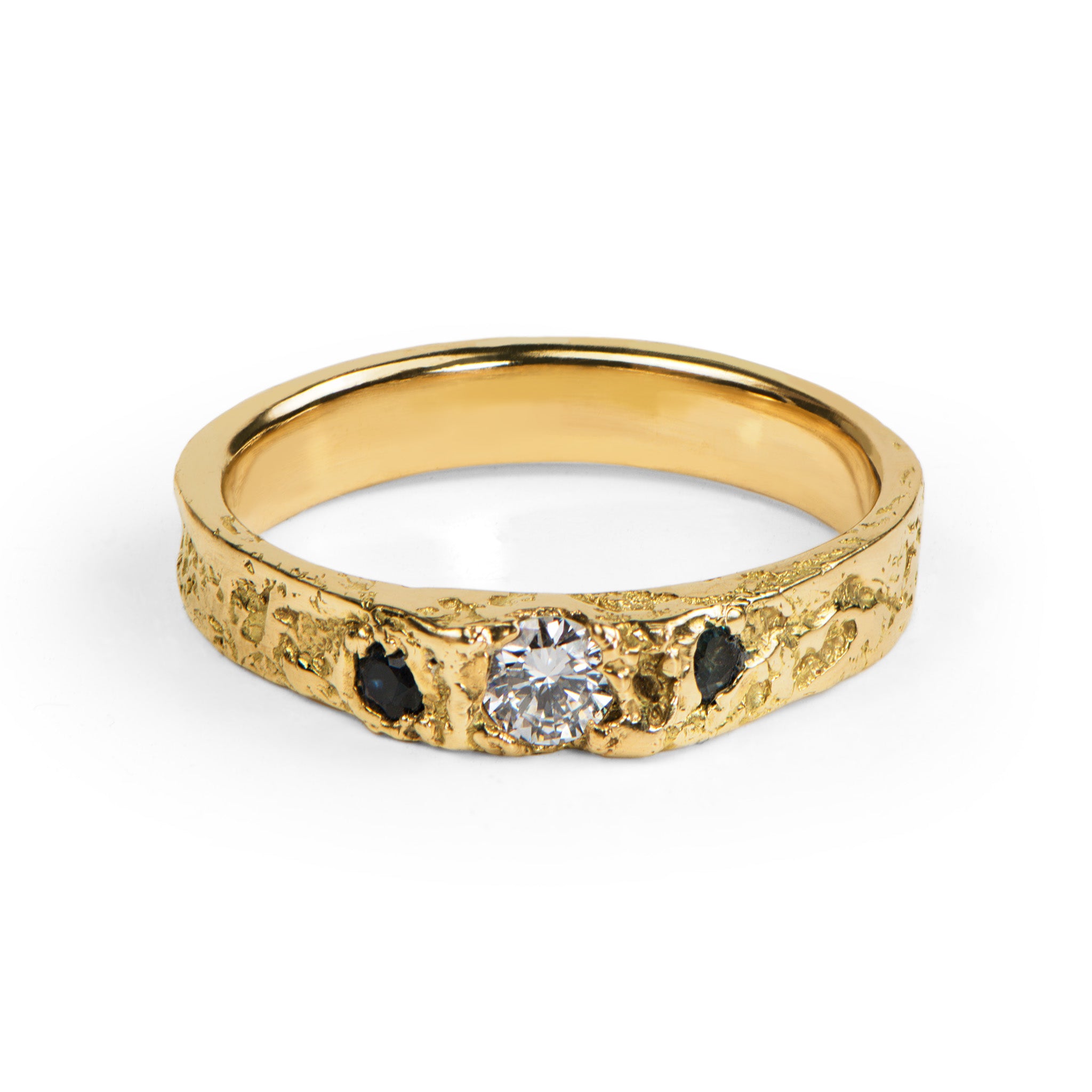 Handcrafted gold engagement ring with a central diamond and blue stones on a white background