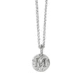 Handcrafted sterling silver initial coin necklace with personalised engraved round pendant hanginf from a silver chain against awhite background.