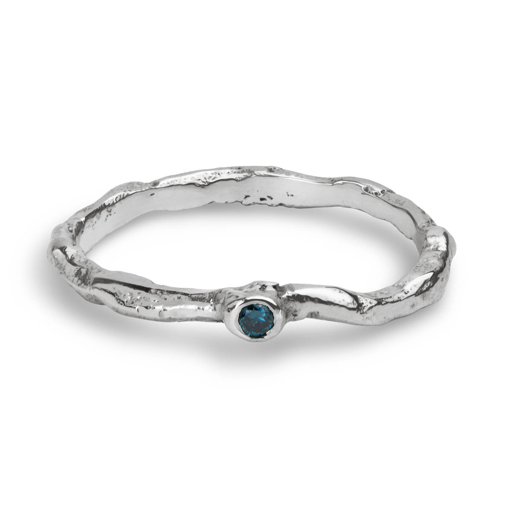 Organic wavy sterling silver ring set with a blue diamond laying on a white background.