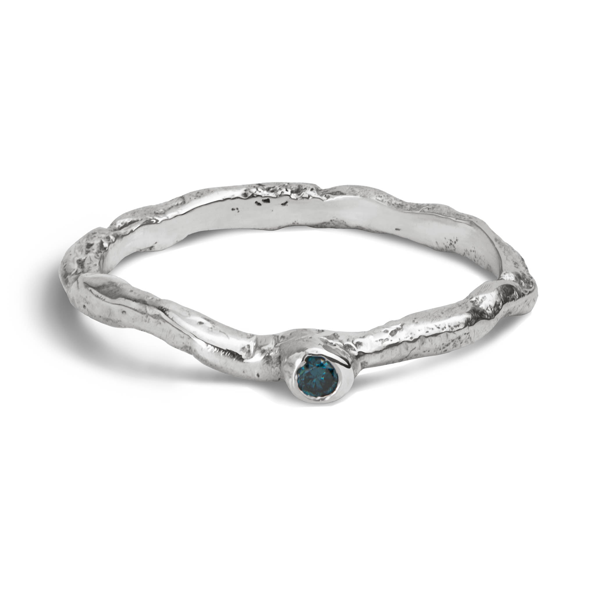 Handcrafted organic textured sterling silver ring set with a blue diamond laying on a white background.