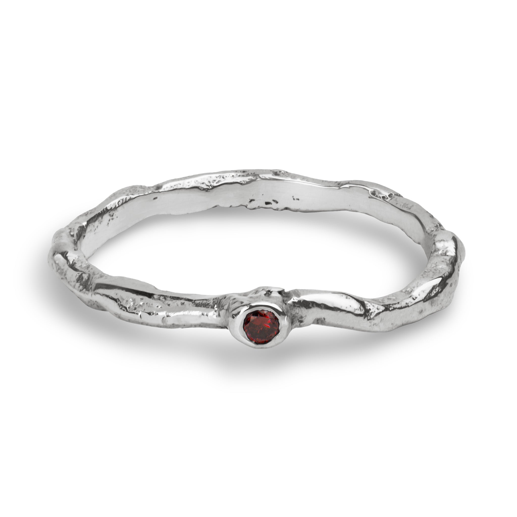A textured sterling silver ring with a wavy, organic band and a small round red gemstone set in the center, shown on a clean white background.