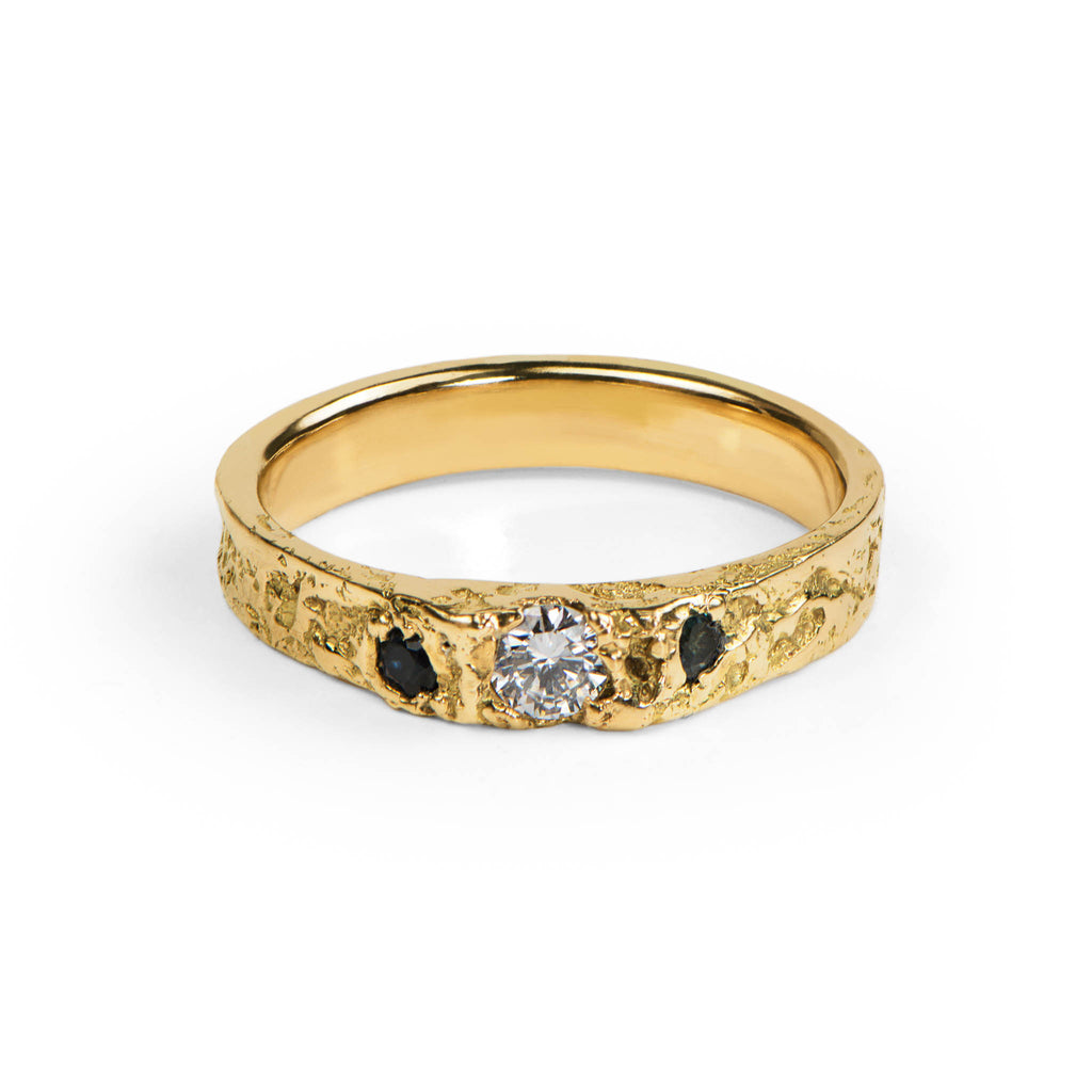 Gold ring with a diamond and tow blue sapphires on a white background