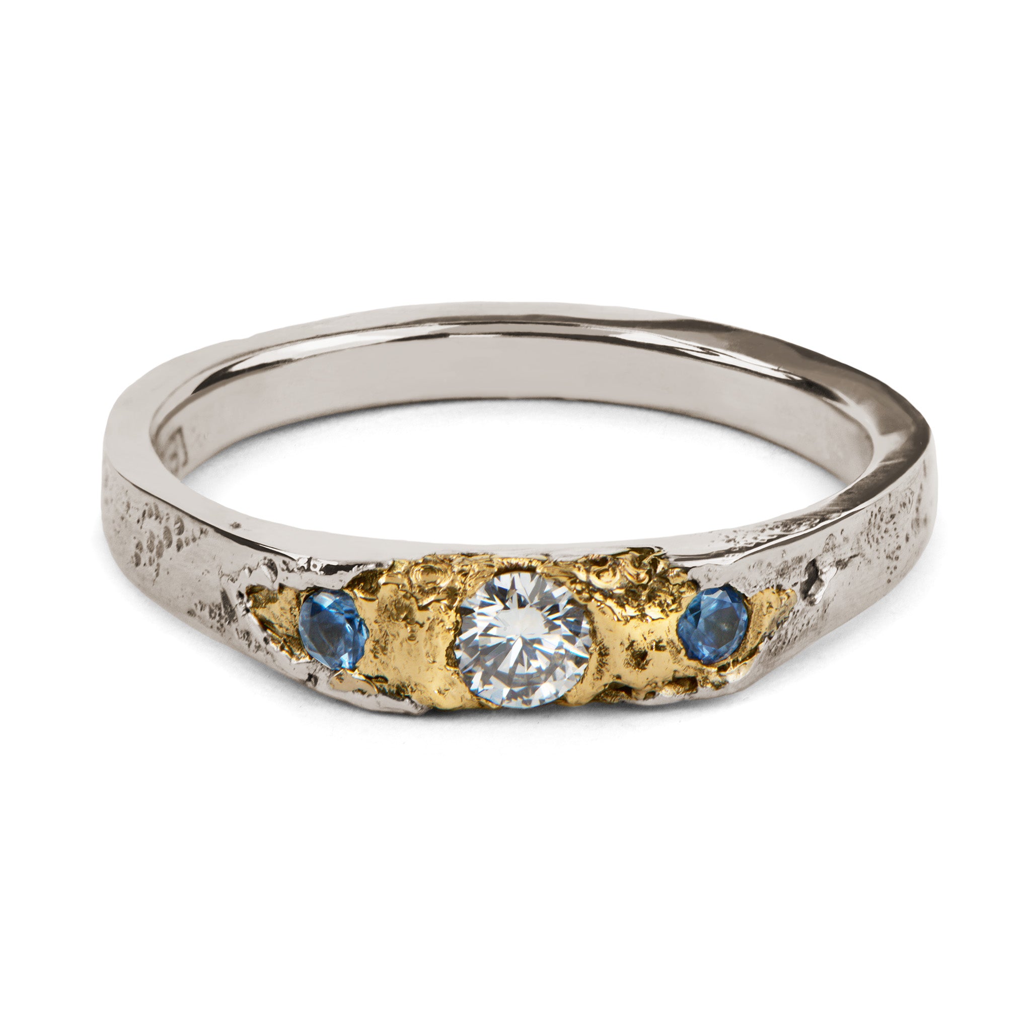 Two tone ring in white gold and yellow gold with one diamond and two blue sapphires in an organic handmade band.