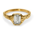 Gold ring with a rectangular diamond on a white background