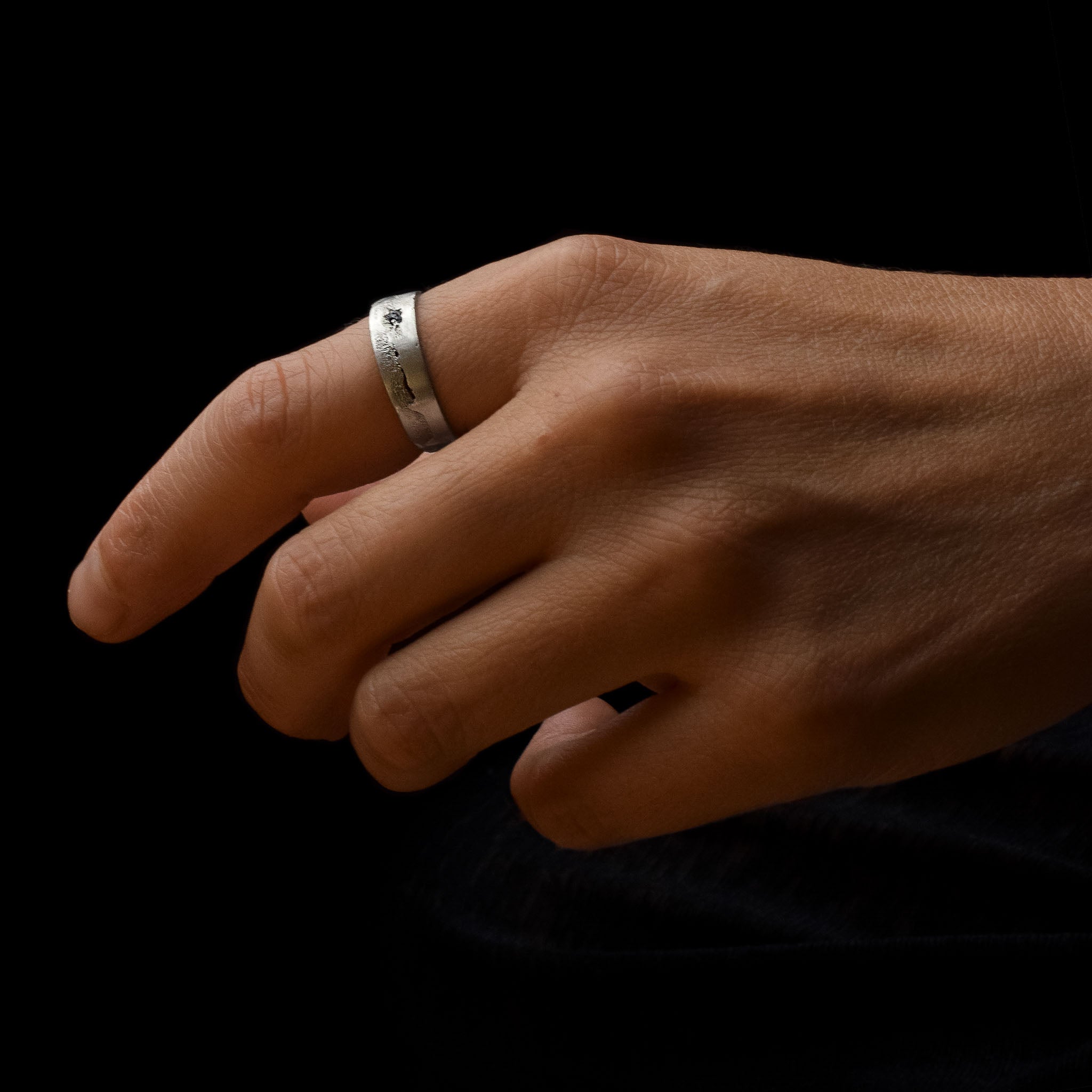Hand wearing a handcrafted, textured silver ring set with a black moissanite  made in Berlin