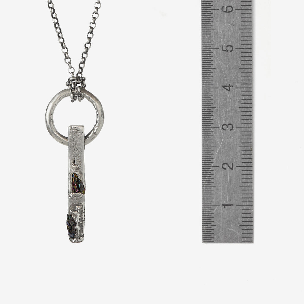Handcrafted sterling silver necklace with sculptural bar pendant and suspended silver ring with aruler to show the size.