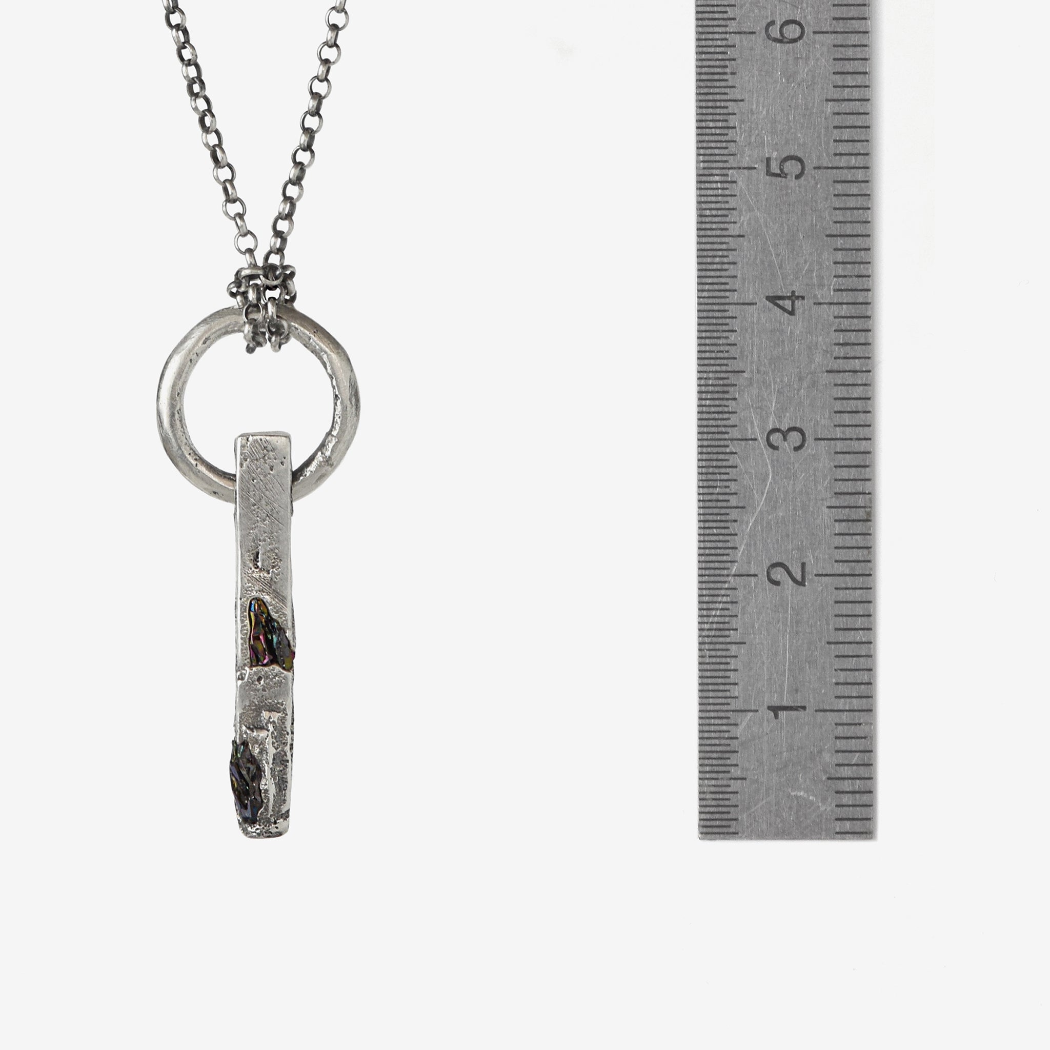 Handcrafted sterling silver necklace with sculptural bar pendant and suspended silver ring with aruler to show the size.