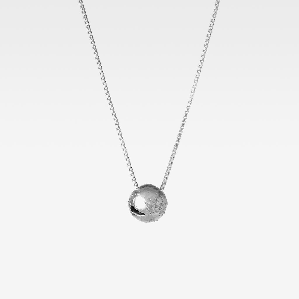 Suspended from a sterling silver curb chain hangs a handcrafted round pendant reminiscent of earth against a white background.