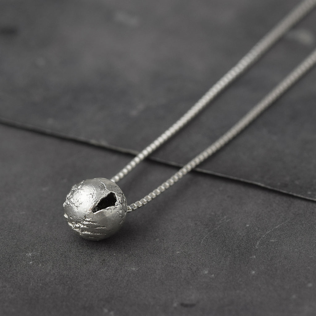 Handcrafted sterling silver hollow sphere pendant with a tactile finish suspended from a sterling silver chain.