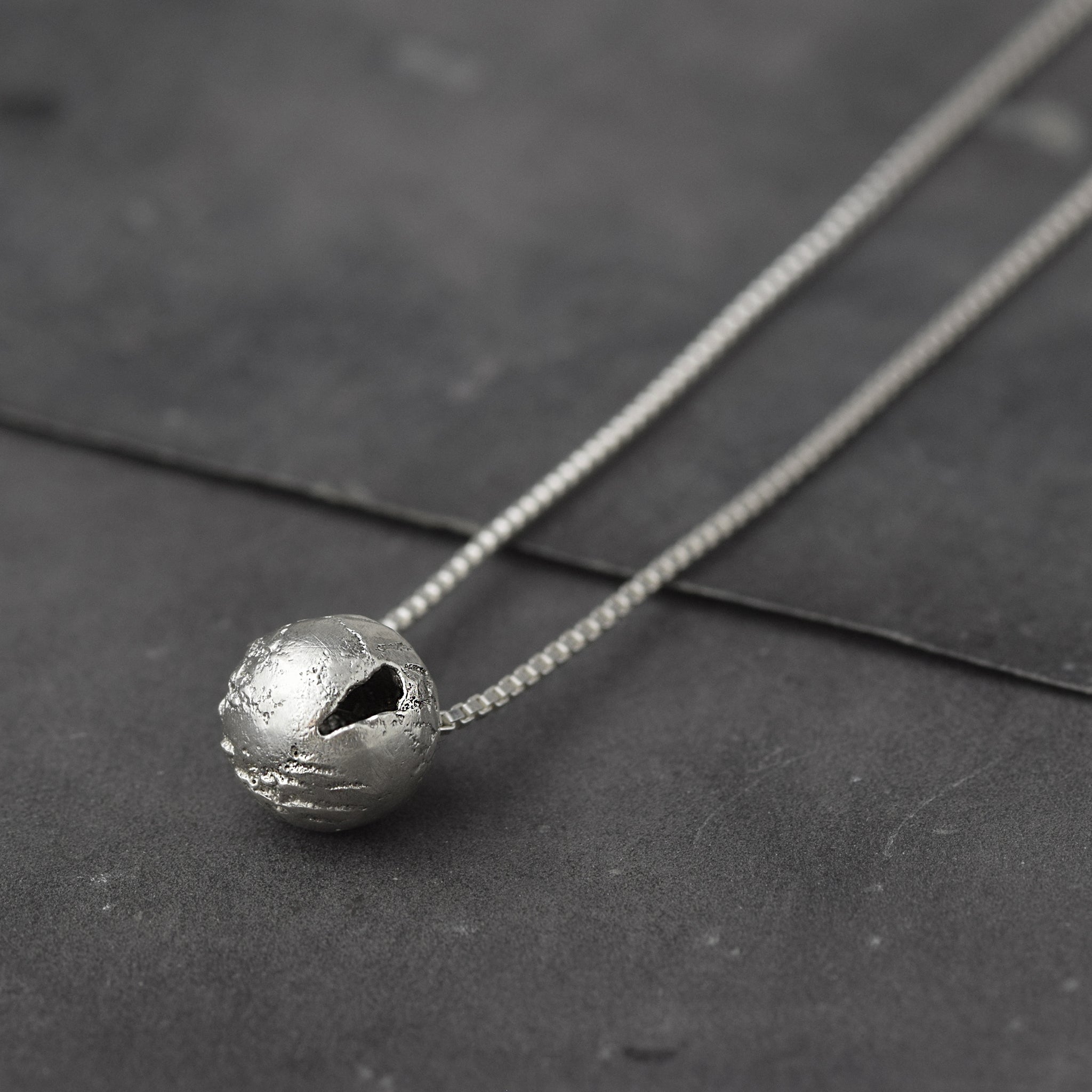 Handcrafted sterling silver hollow sphere pendant with a tactile finish suspended from a sterling silver chain.