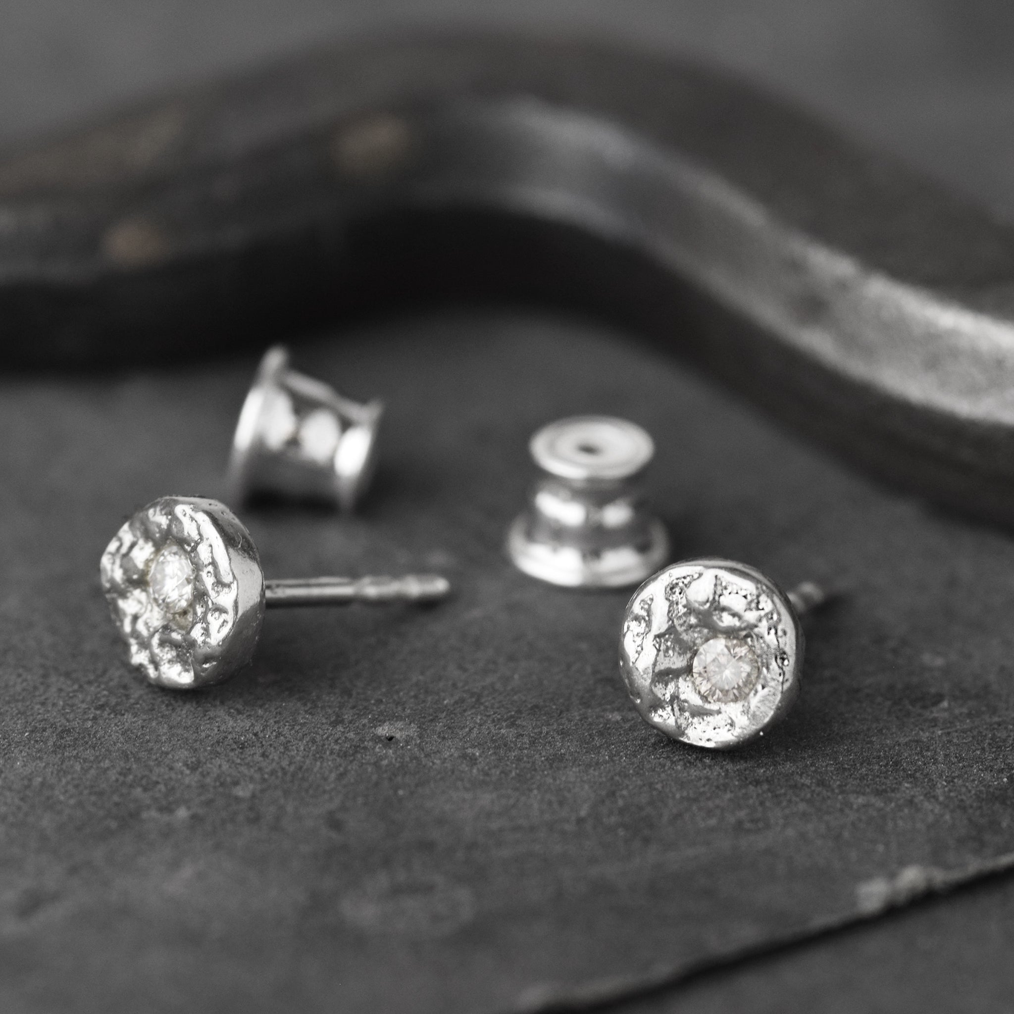 Handcrafted sterling silver disc stud earrings set with brilliant cut moissanites and a natural cast finish.