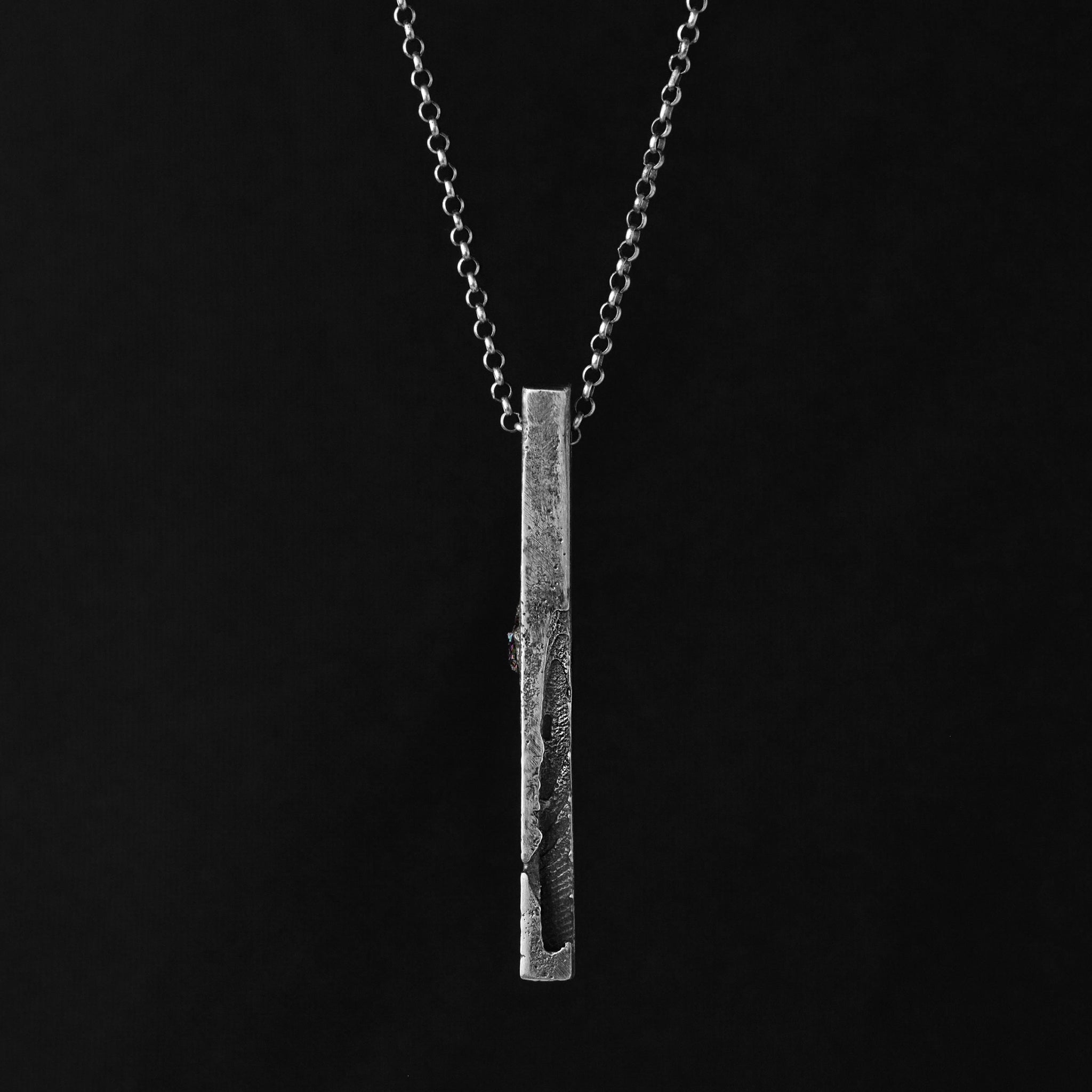 Textured silver monolith pendant gainst a blöack background