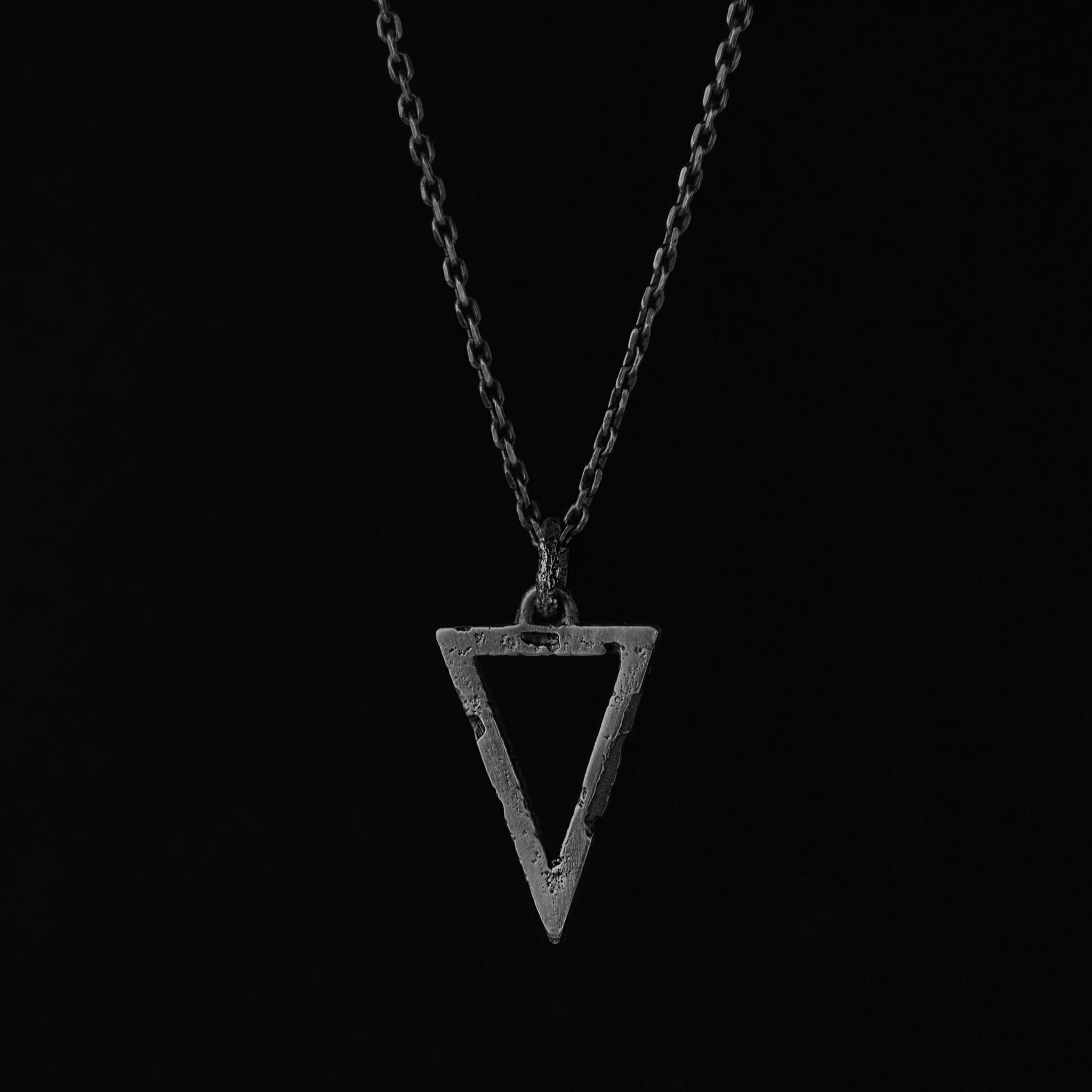 Silver triangle pendant with an organic textured finish suspended from a sterling silver chain handcrafted in Berlin.