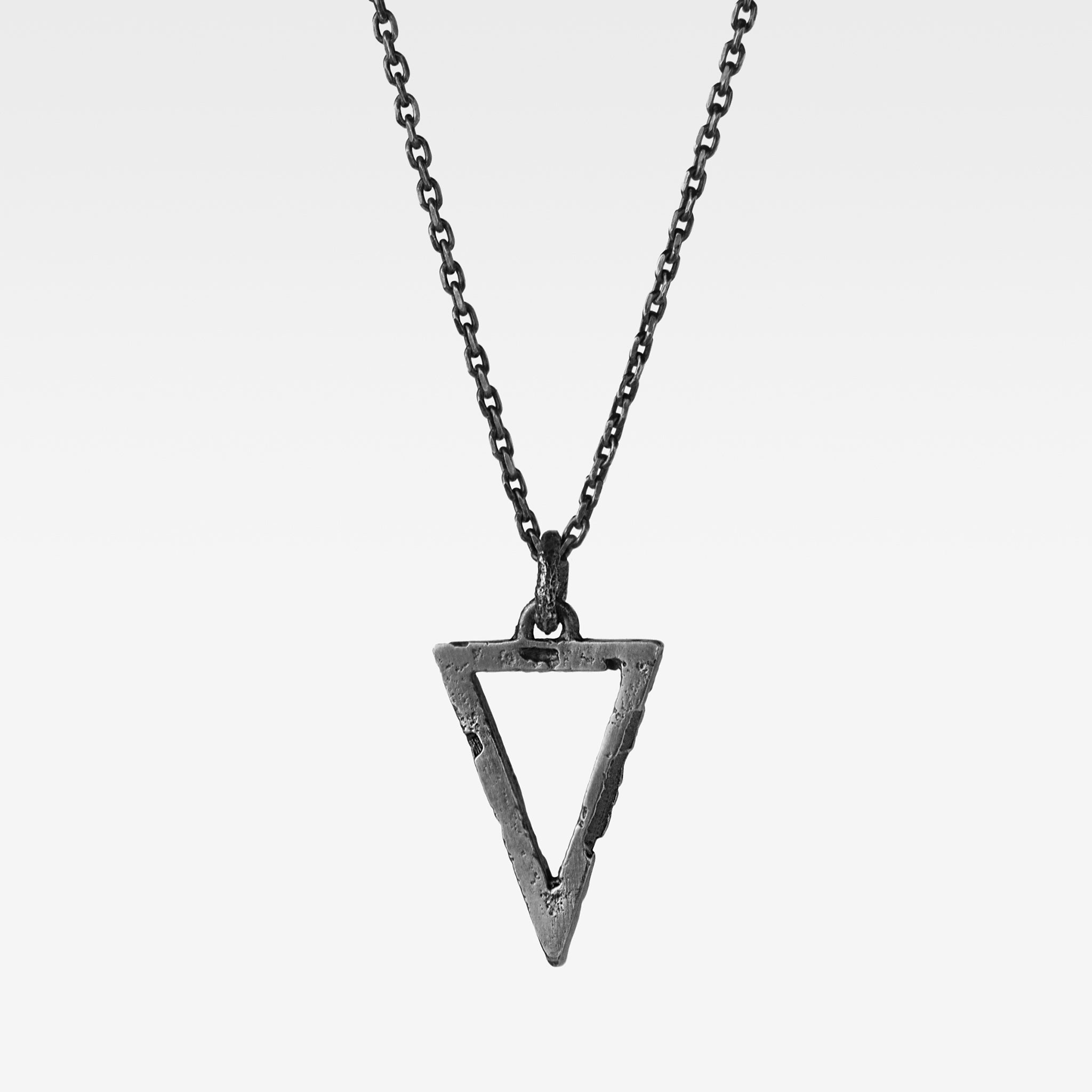 Handcrafted small sterling silver triangle pendant with an organic textured finish suspended from a sterling silver chain against a white background.