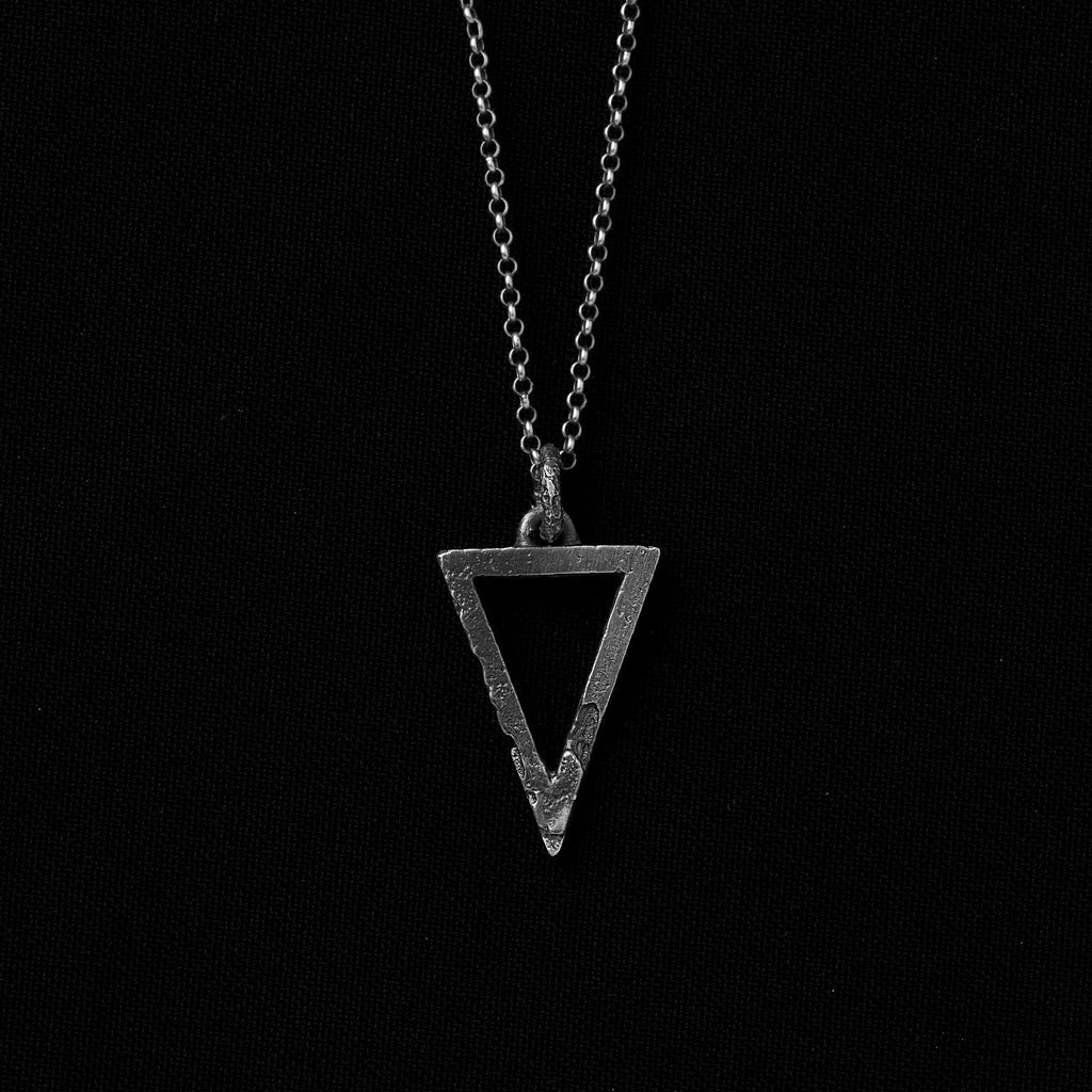 Handcrafted small sterling silver triangle pendant with an organic textured finish suspended from a sterling silver chain on a black background.