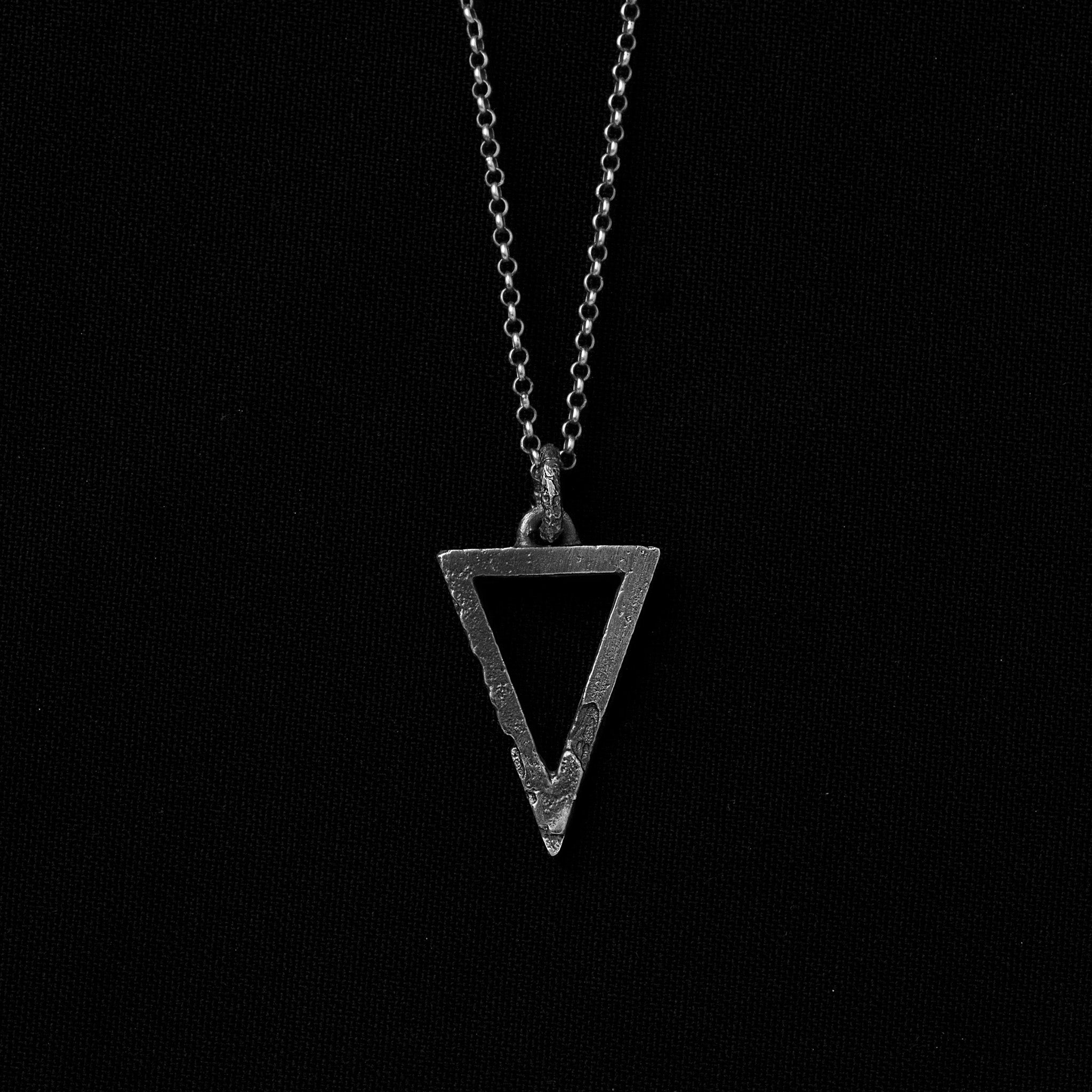 Handcrafted small sterling silver triangle pendant with an organic textured finish suspended from a sterling silver chain on a black background.