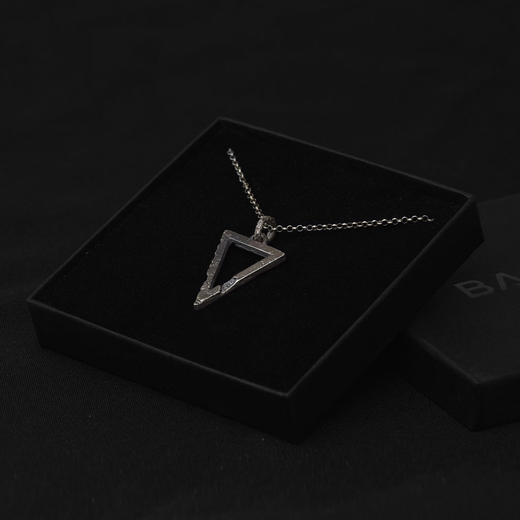 Handcrafted small sterling silver triangle pendant with an organic textured finish in a luxurious black jewelry pouch.