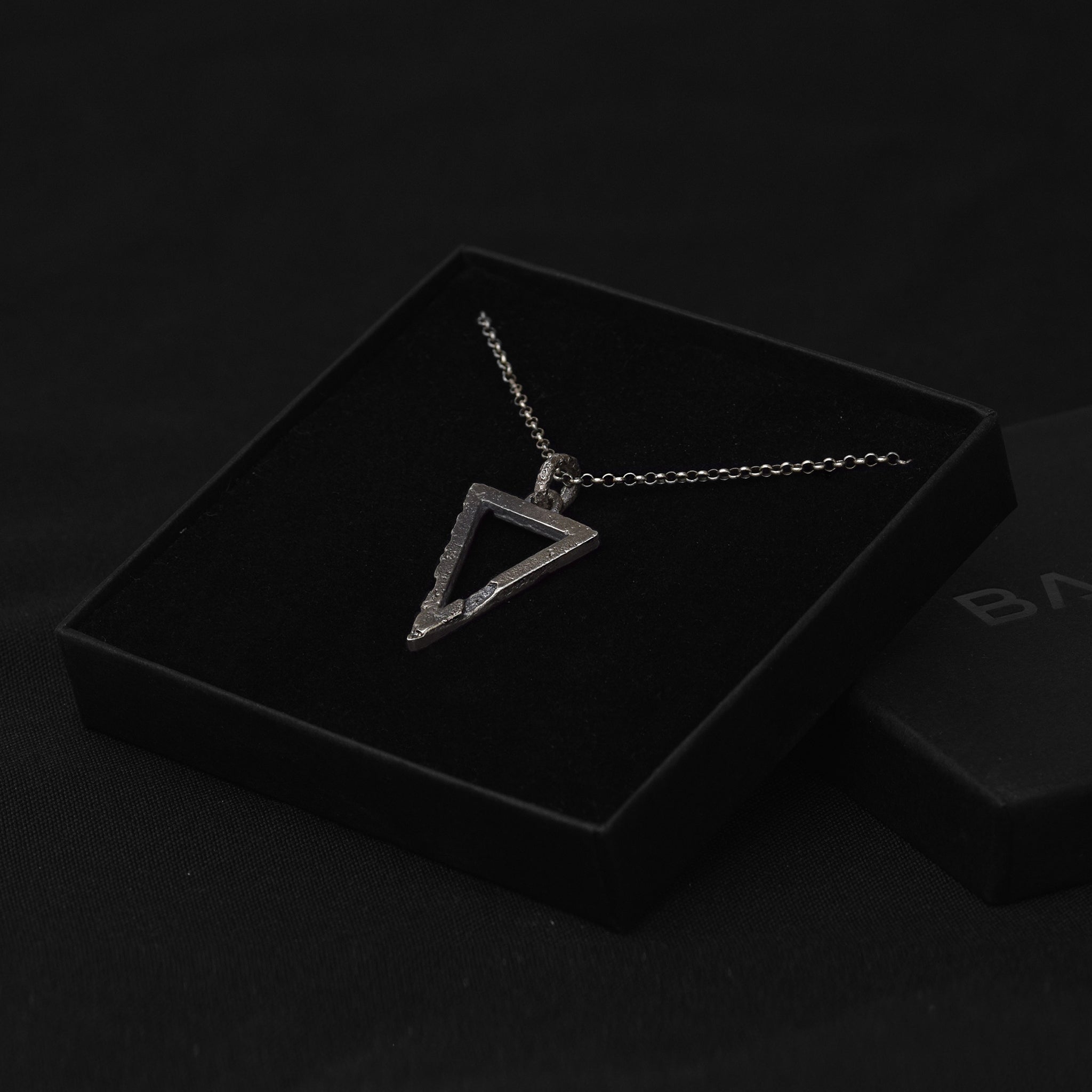 Handcrafted small sterling silver triangle pendant with an organic textured finish in a luxurious black jewelry pouch.