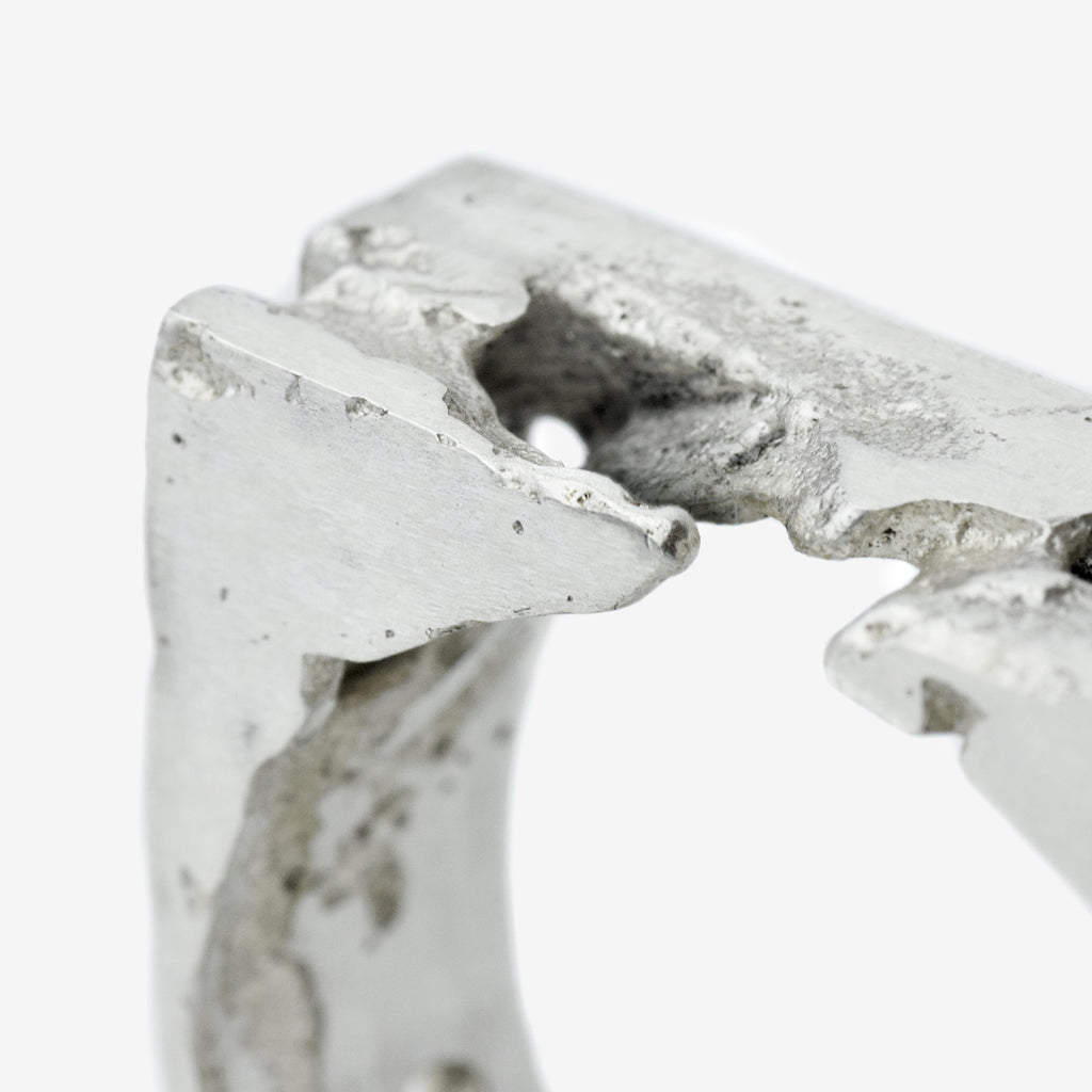 Close-up of a handcrafted sterling silver ring with sculpted 8 mm wide band featuring raw and polished textures.