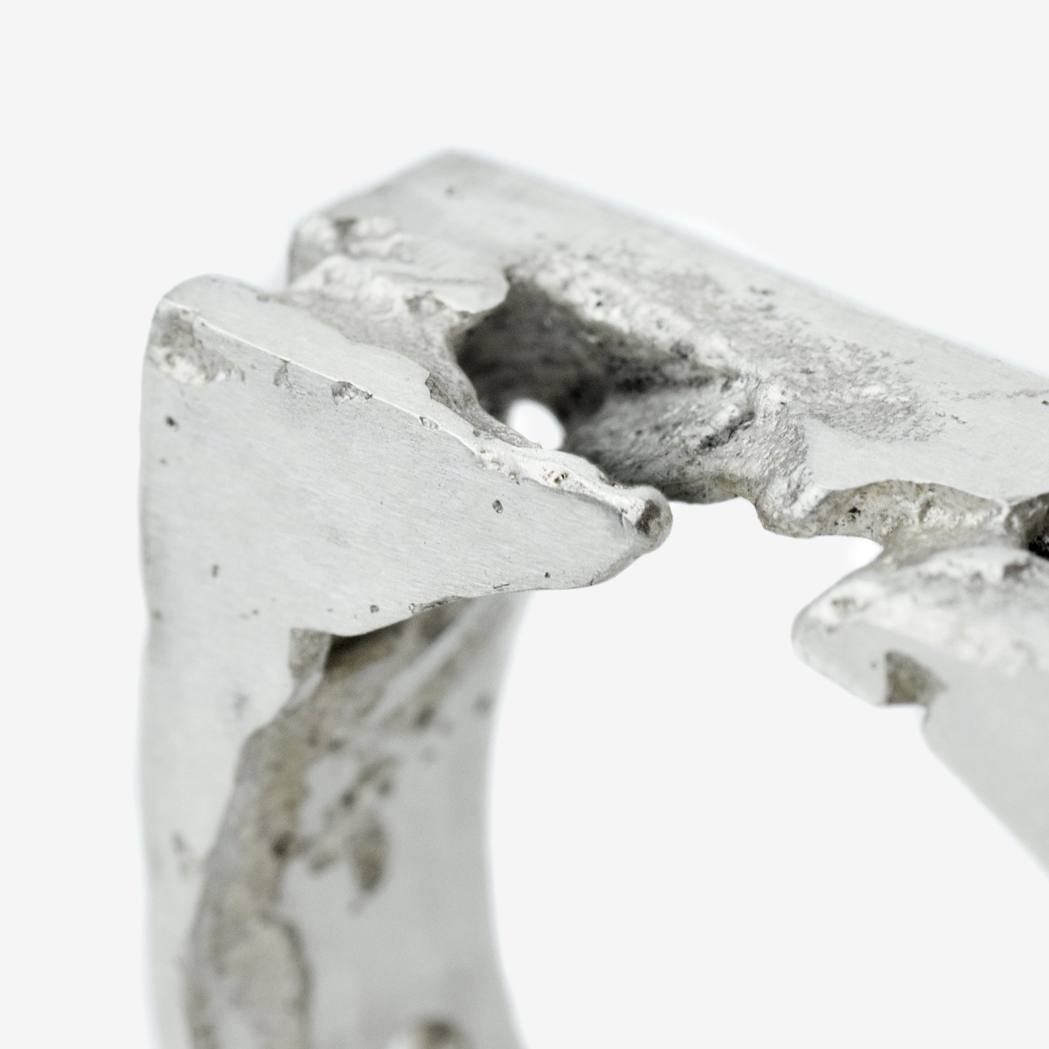 Close-up of a handcrafted sterling silver ring with sculpted 8 mm wide band featuring raw and polished textures.