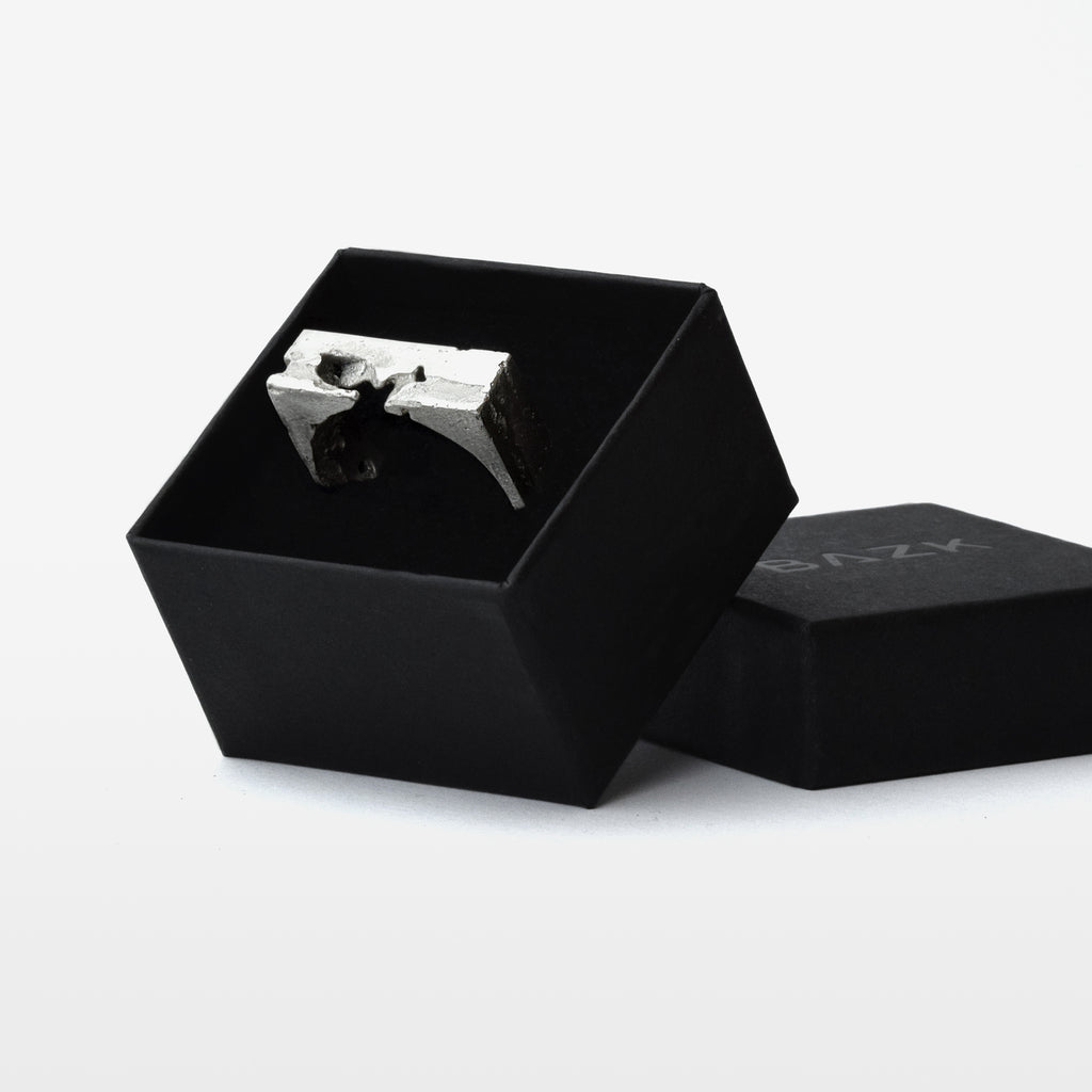 Sterling silver ring with a geometric profile in a black luxury jewelry box on a white background.